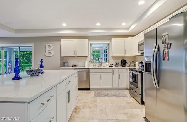 kitchen featuring a tray ceiling, sink, white cabinets, and appliances with stainless steel finishes