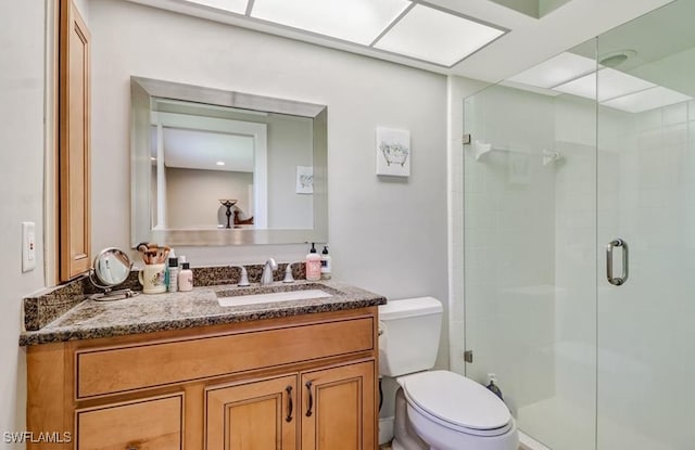 bathroom with a shower with door, vanity, and toilet