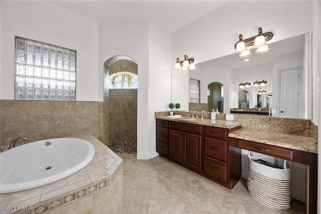 bathroom with tile patterned flooring, vanity, and tiled tub