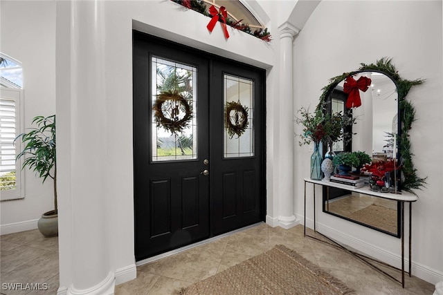 foyer entrance with plenty of natural light, light tile patterned flooring, and decorative columns