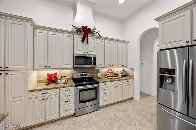 kitchen with stainless steel appliances, tasteful backsplash, ornamental molding, light stone countertops, and light tile patterned floors