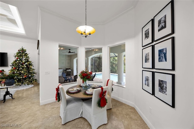 tiled dining space with ceiling fan with notable chandelier and crown molding