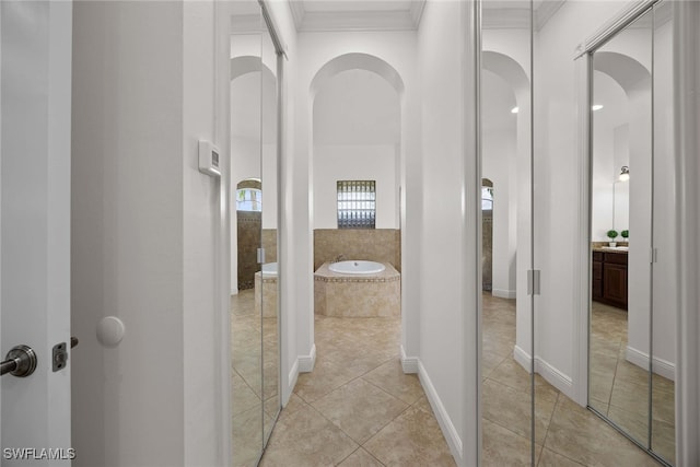 bathroom featuring tile patterned floors, crown molding, and a relaxing tiled tub