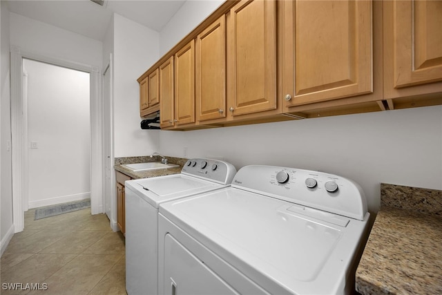 clothes washing area featuring light tile patterned floors, washing machine and dryer, cabinets, and sink