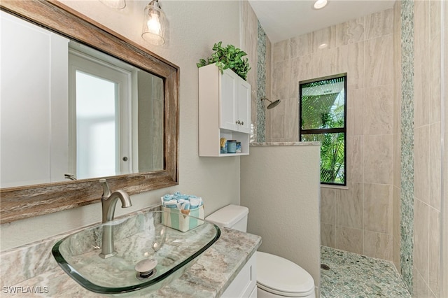 bathroom featuring toilet, vanity, and a tile shower