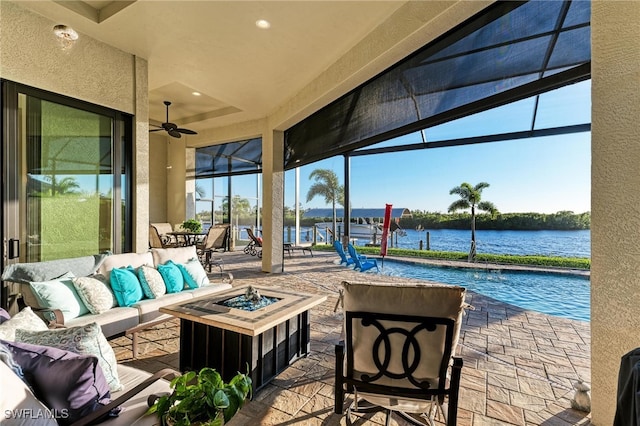 view of patio / terrace featuring an outdoor living space with a fire pit, a water view, and ceiling fan