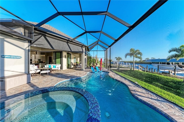 view of swimming pool with an in ground hot tub, a water view, a lawn, a lanai, and a patio area