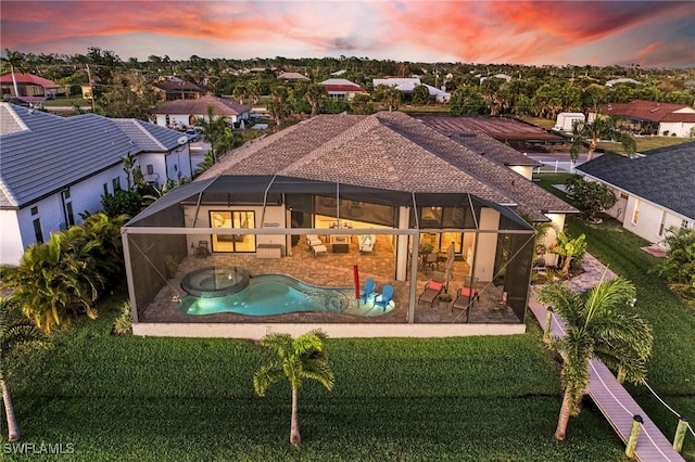 pool at dusk featuring a patio, a yard, and an in ground hot tub