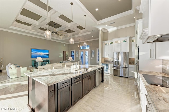 kitchen featuring stainless steel appliances, dark brown cabinets, coffered ceiling, sink, and a kitchen island with sink