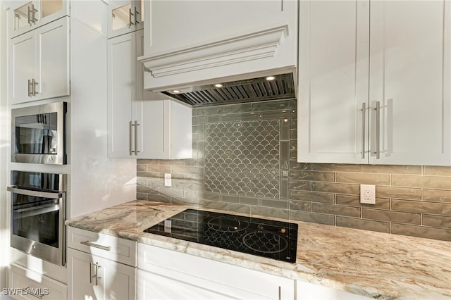 kitchen with white cabinets, stainless steel appliances, tasteful backsplash, and light stone counters