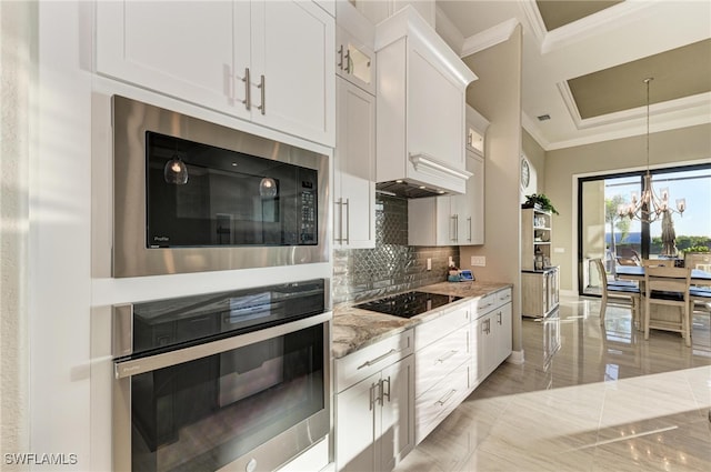 kitchen featuring an inviting chandelier, ornamental molding, light stone countertops, white cabinetry, and appliances with stainless steel finishes