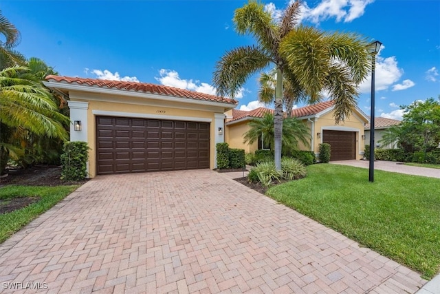 mediterranean / spanish home featuring a garage and a front lawn