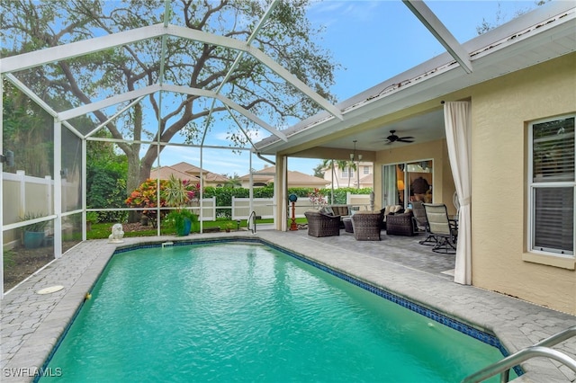 view of pool with an outdoor living space, glass enclosure, ceiling fan, and a patio area