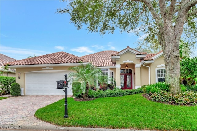 mediterranean / spanish home featuring a front lawn, a garage, and french doors