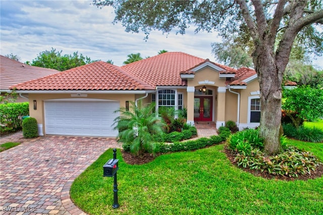 mediterranean / spanish home featuring a garage, a front yard, and french doors