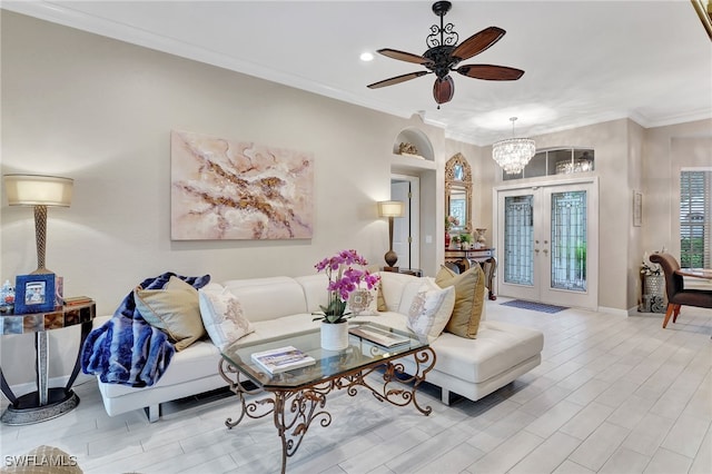 living room featuring french doors, light wood-type flooring, ceiling fan with notable chandelier, and ornamental molding