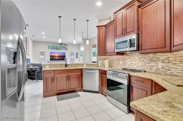 kitchen featuring decorative backsplash, stainless steel appliances, ceiling fan, sink, and hanging light fixtures