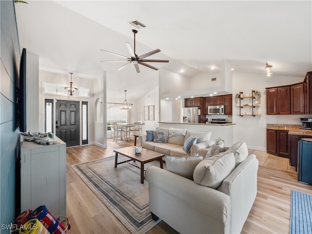 living room with ceiling fan with notable chandelier, light hardwood / wood-style flooring, and high vaulted ceiling