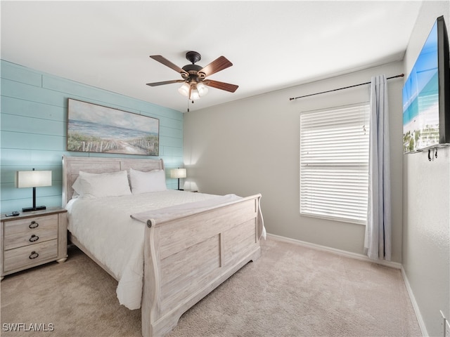 bedroom with light carpet, ceiling fan, and wood walls