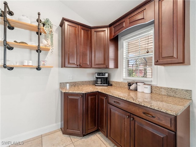 kitchen featuring light stone countertops, light tile patterned floors, and vaulted ceiling