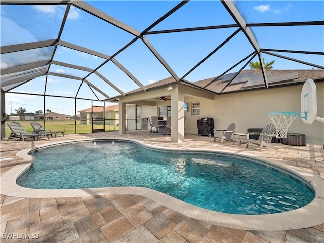 view of pool with ceiling fan, glass enclosure, and a patio