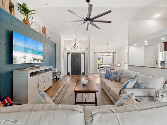 living room with lofted ceiling, sink, ceiling fan with notable chandelier, and light hardwood / wood-style floors