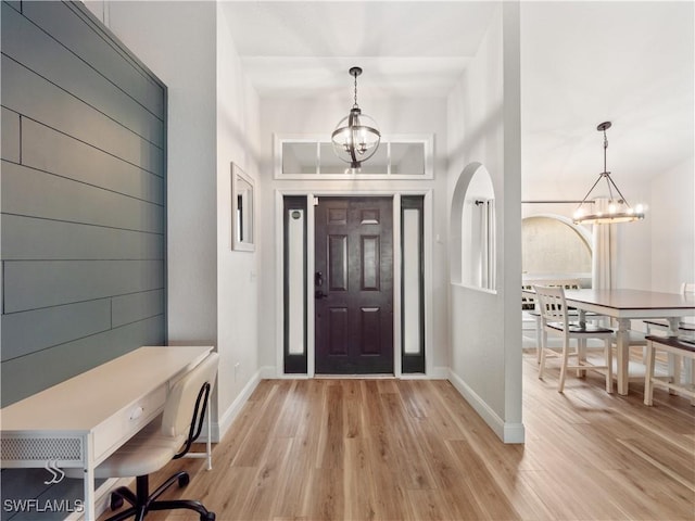 entrance foyer with light wood-type flooring, an inviting chandelier, and a towering ceiling