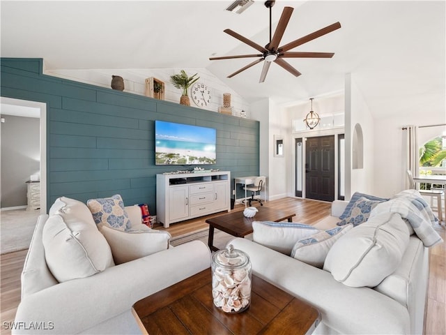 living room featuring ceiling fan, lofted ceiling, and light hardwood / wood-style flooring