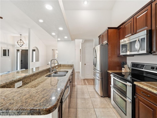 kitchen featuring light stone countertops, pendant lighting, stainless steel appliances, sink, and light tile patterned floors