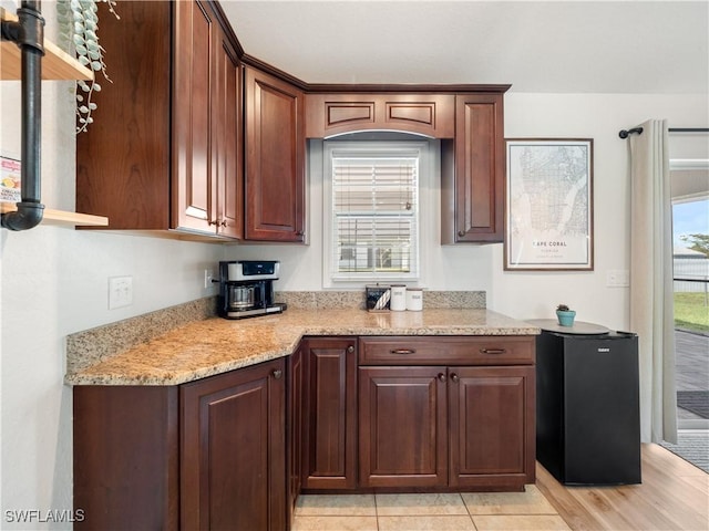 kitchen featuring light stone counters, refrigerator, and light tile patterned flooring