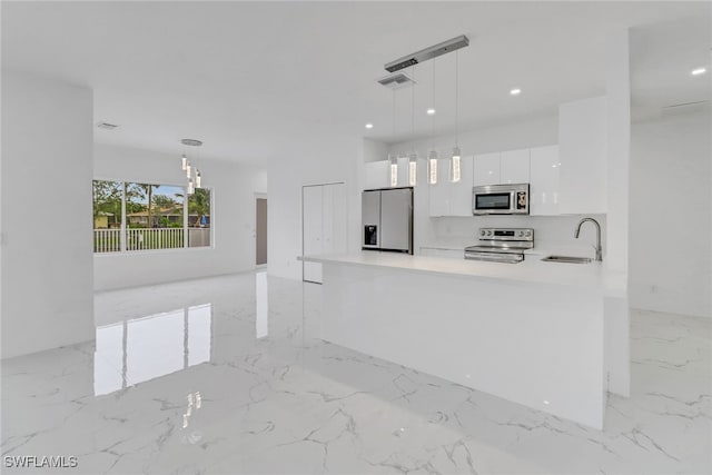 kitchen with pendant lighting, white cabinets, sink, and stainless steel appliances