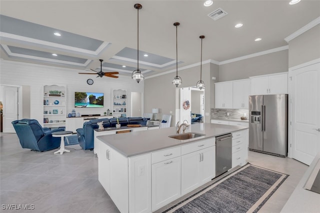 kitchen with stainless steel appliances, sink, pendant lighting, white cabinets, and an island with sink