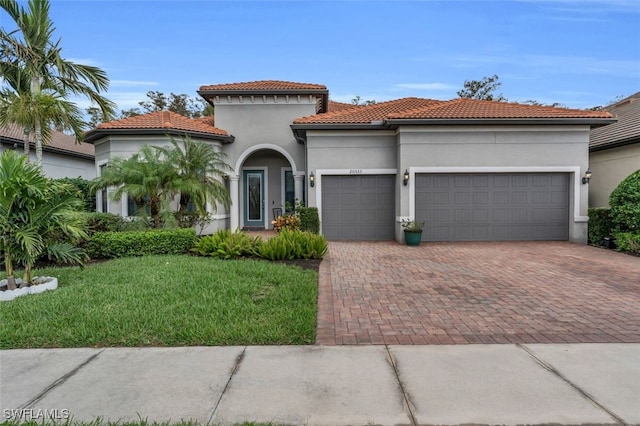 20533 Wilderness Ct, Estero, FL 33928 - mediterranean / spanish-style house with decorative driveway, an attached garage, a front yard, stucco siding, and a tiled roof