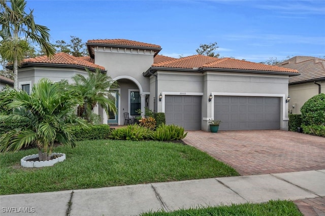 20533 Wilderness Ct, Estero, FL 33928 - mediterranean / spanish-style home with an attached garage, decorative driveway, stucco siding, a front yard, and a tiled roof