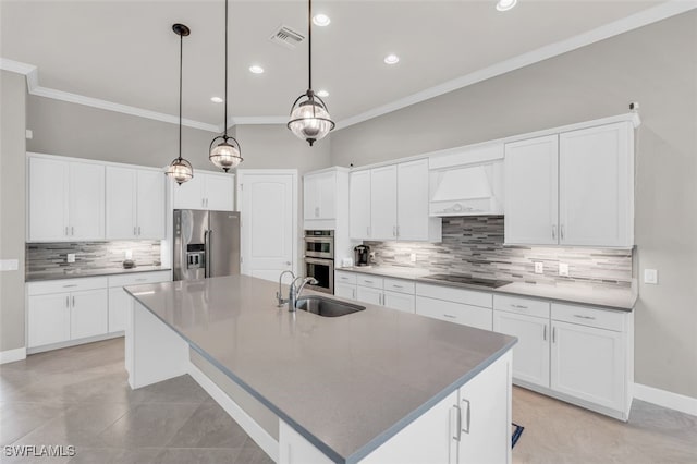 kitchen featuring custom exhaust hood, stainless steel appliances, sink, white cabinetry, and an island with sink