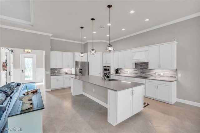 kitchen with white cabinetry, hanging light fixtures, stainless steel appliances, a kitchen island with sink, and light tile patterned floors