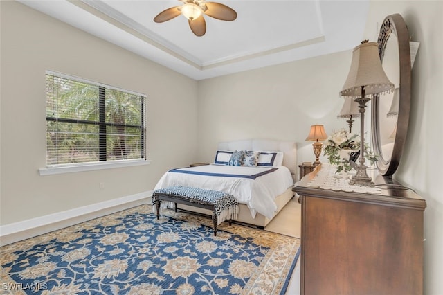 bedroom with a raised ceiling, ceiling fan, and wood-type flooring