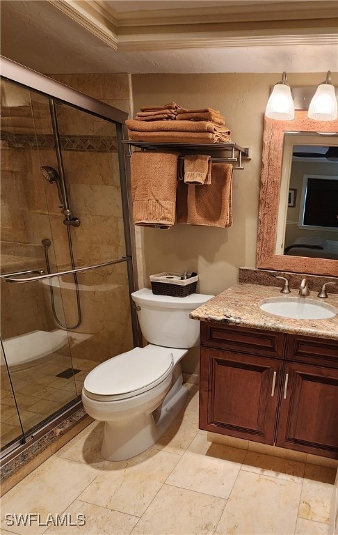 bathroom with ornamental molding, vanity, toilet, and a shower with shower door