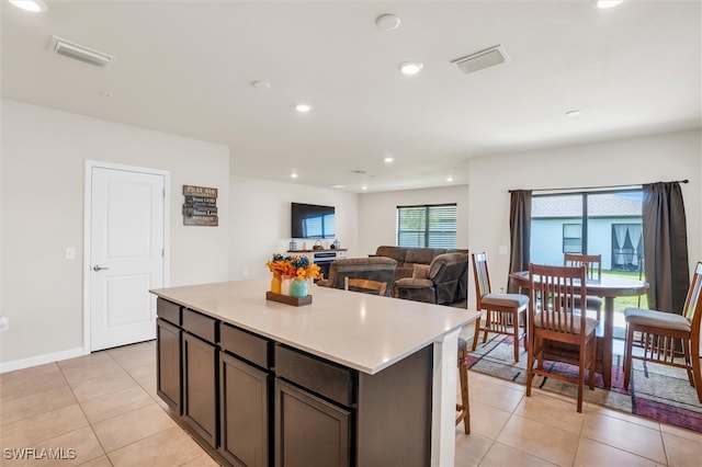 kitchen featuring dark brown cabinetry, light tile patterned floors, and a kitchen island