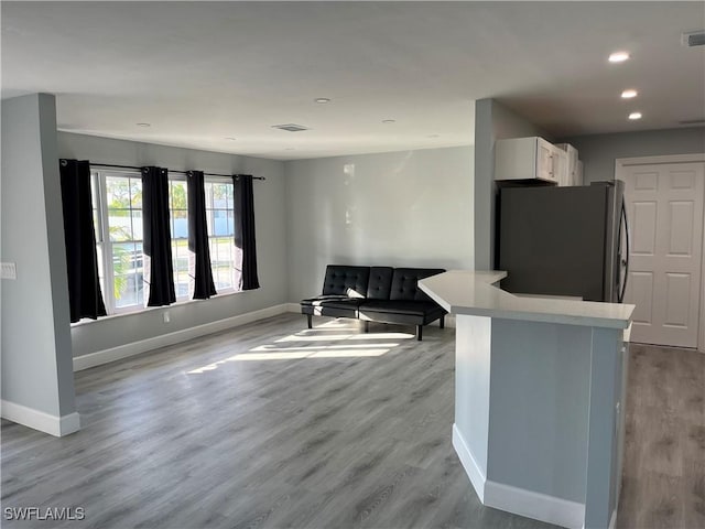 kitchen with white cabinets, stainless steel fridge, and light hardwood / wood-style flooring