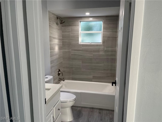 full bathroom featuring toilet, hardwood / wood-style flooring, tiled shower / bath, and vanity