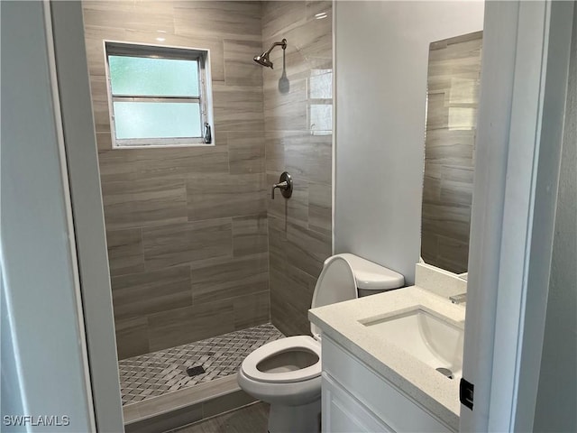 bathroom with tiled shower, vanity, and toilet