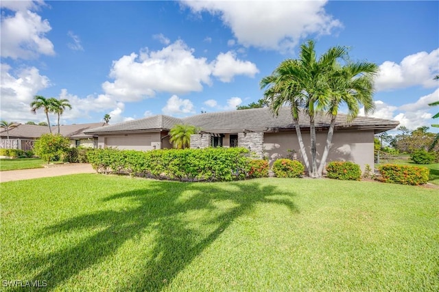 view of front of home featuring a garage, driveway, a front lawn, and stucco siding