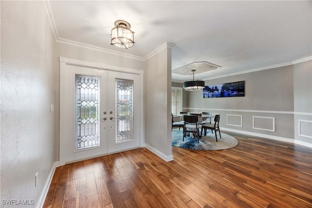 entryway featuring hardwood / wood-style flooring, an inviting chandelier, crown molding, and french doors