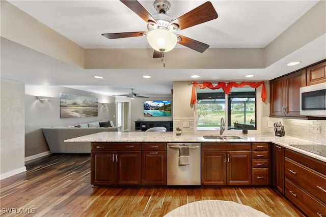 kitchen featuring appliances with stainless steel finishes, a tray ceiling, a sink, and wood finished floors