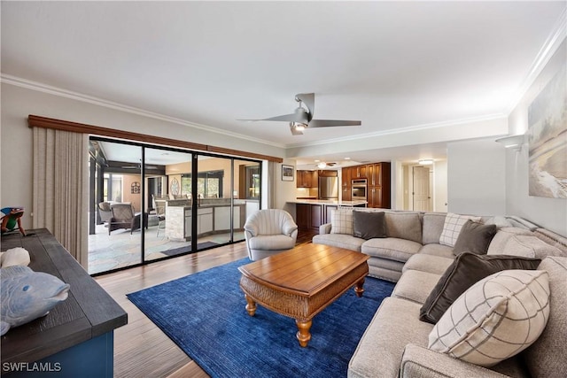 living area featuring crown molding, light wood finished floors, and ceiling fan