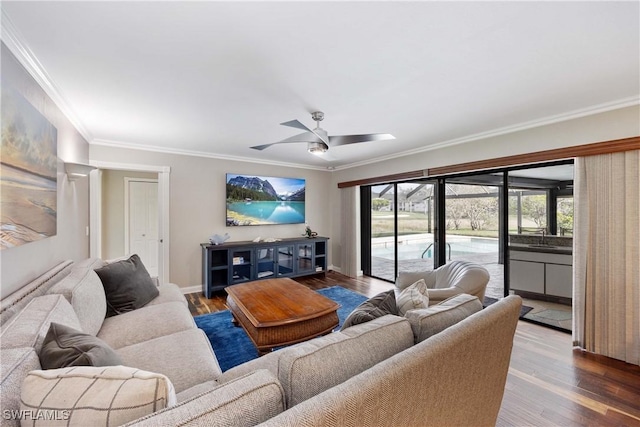 living area with baseboards, wood finished floors, a ceiling fan, and crown molding