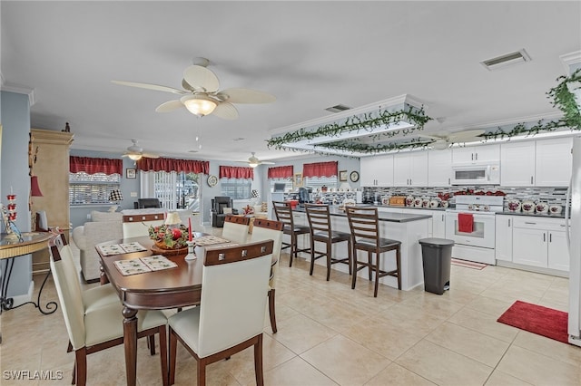 tiled dining area featuring crown molding and ceiling fan