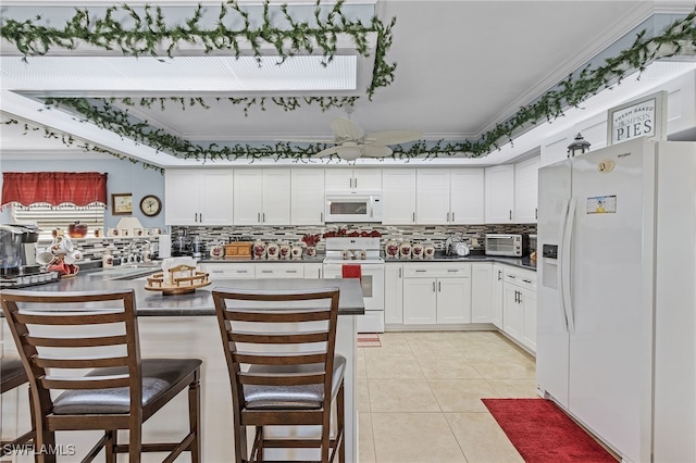 kitchen with crown molding, light tile patterned floors, a kitchen breakfast bar, white appliances, and white cabinets