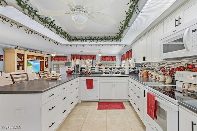 kitchen featuring white cabinetry, kitchen peninsula, white appliances, and a tray ceiling